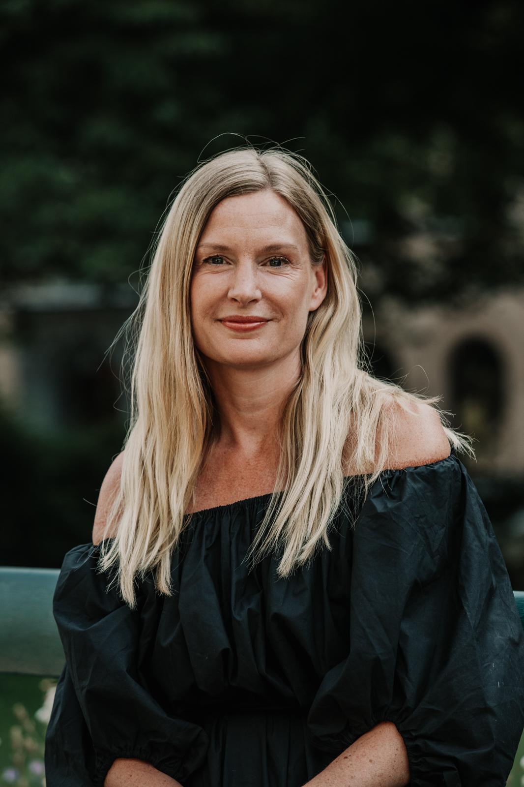 Julia Munck, founder of Saged, in a black dress outdoors